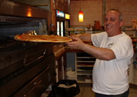 Tony, the owner, placing a fresh pizza into the oven.